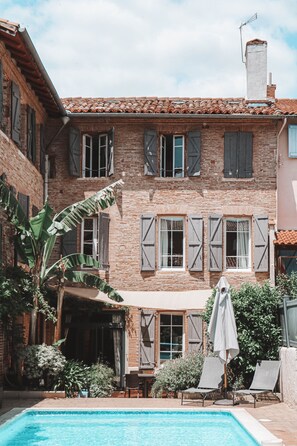 Experience the charm of a traditional European-style building with a tranquil courtyard featuring a swimming pool and lounge area.