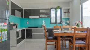 A modern kitchen with a dining area, featuring a refrigerator, microwave, sink, and a dining table with chairs. - Facetime Home (Da Nang)