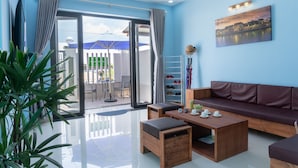 A modern living room with a sofa, coffee table, and a dining area with chairs. - Facetime Home (Da Nang)