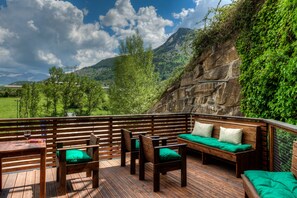 A wooden deck with seating and a table, overlooking a mountainous landscape. - Aparthotel Tres Quiñones (Sallent de Gallego)