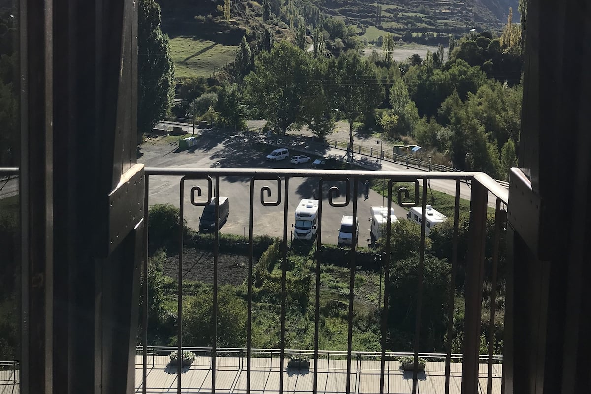 A balcony with a view of a parking lot and mountains.