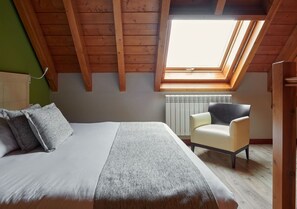 A bedroom with a bed, a chair, a radiator, and a skylight. - Aparthotel Tres Quiñones (Sallent de Gallego)