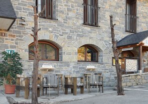 A stone building with outdoor seating and a sign that reads "ABERTO". - Aparthotel Tres Quiñones (Sallent de Gallego)