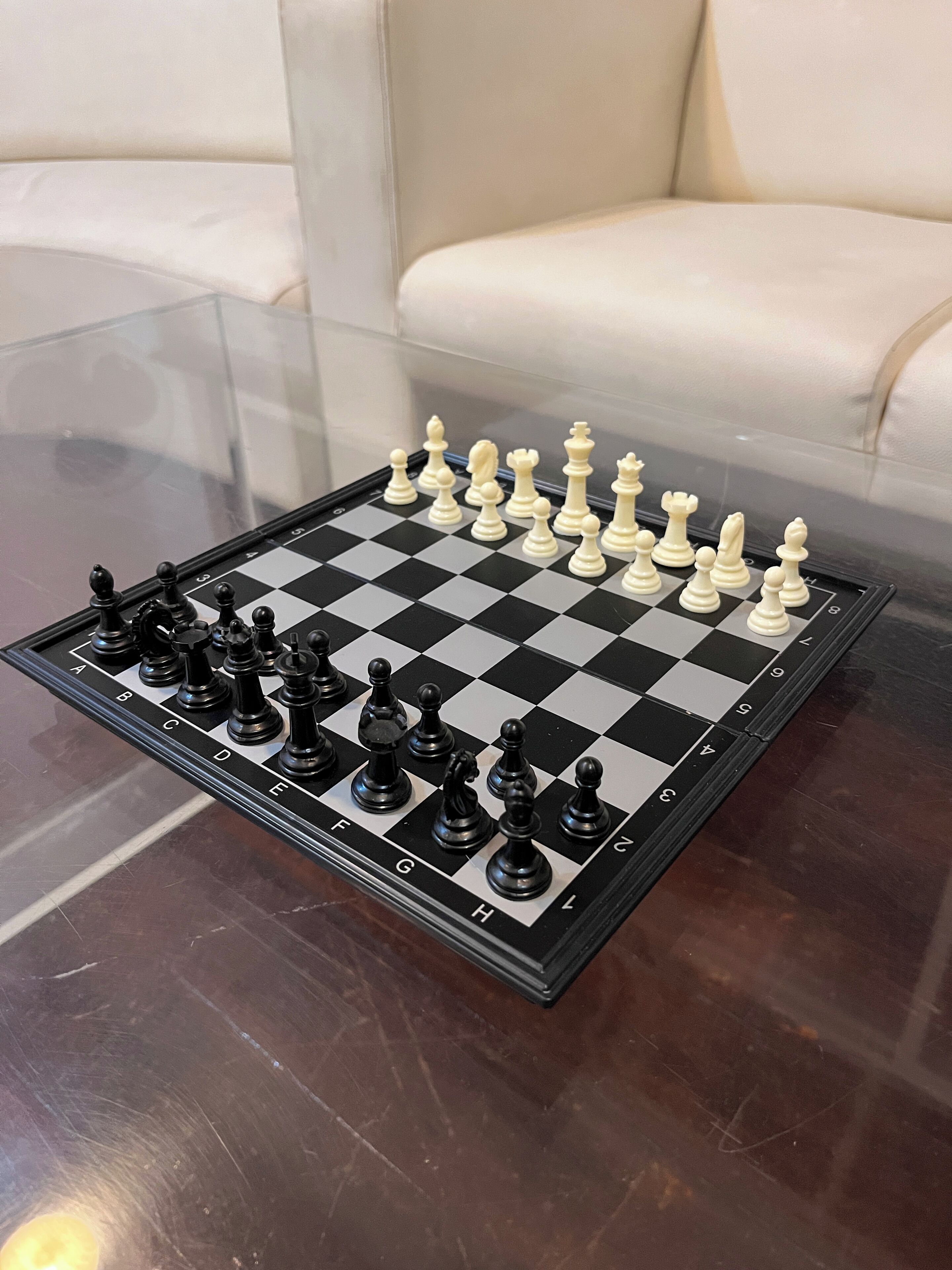 A chessboard on a glass table with a checkered floor.