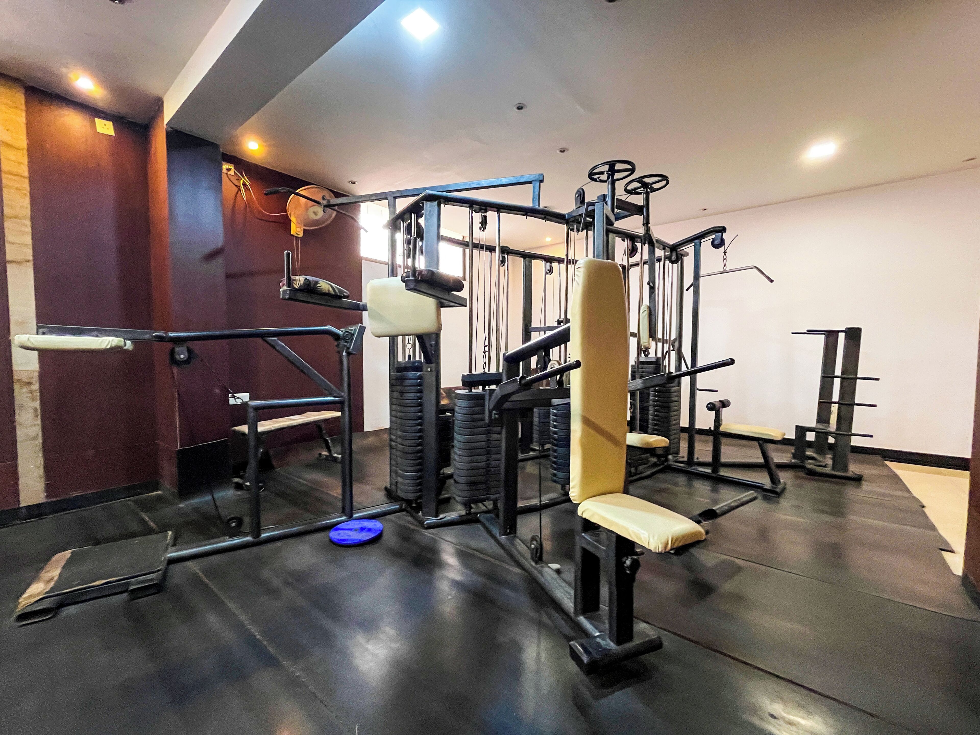 A gym with various exercise equipment, including a bench press, squat rack, and weight plates.