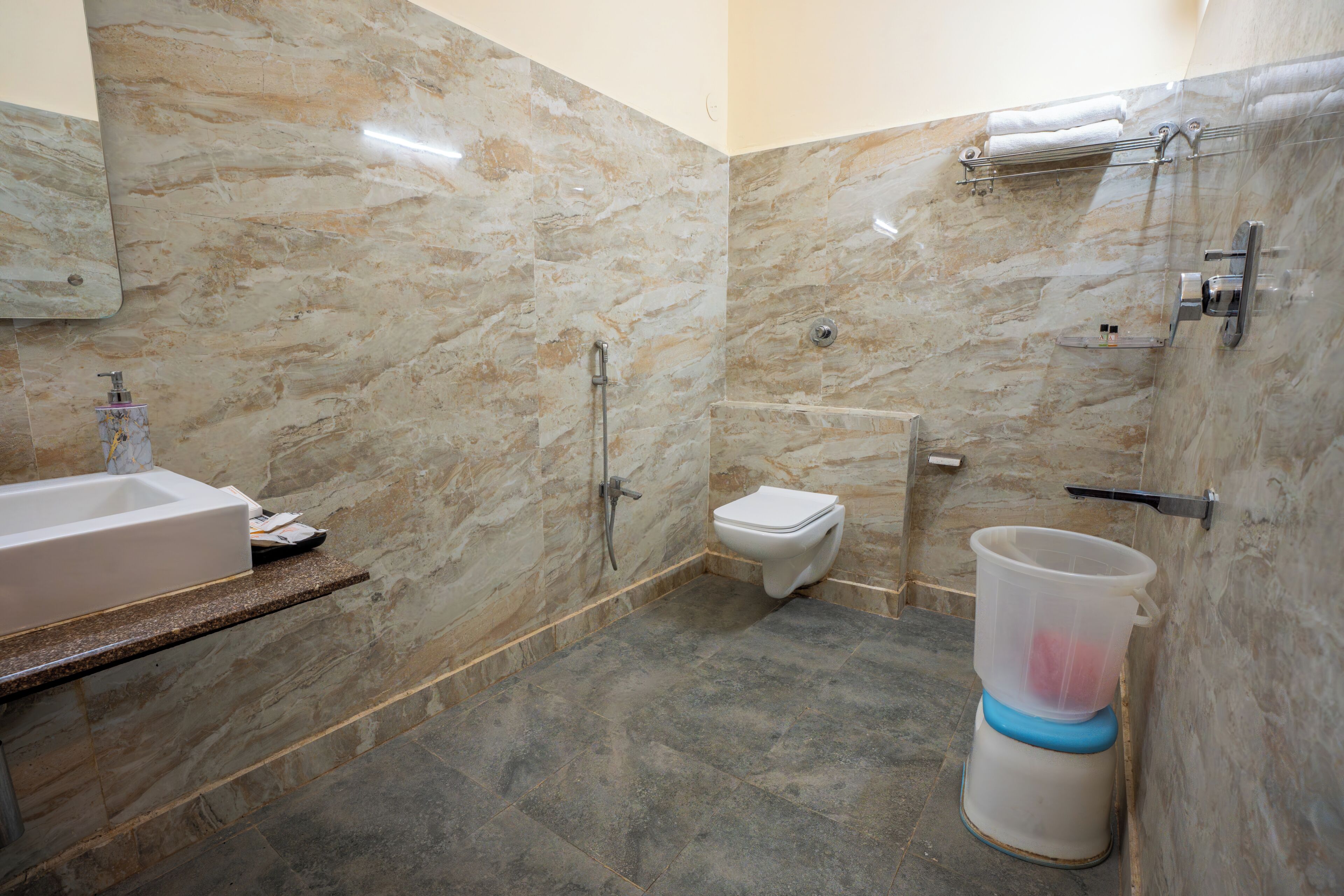 A bathroom with a marble wall, a toilet, a shower, and a bathtub.