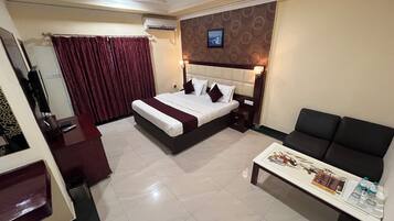 A hotel room with a bed, a sofa, a small table, and a TV.