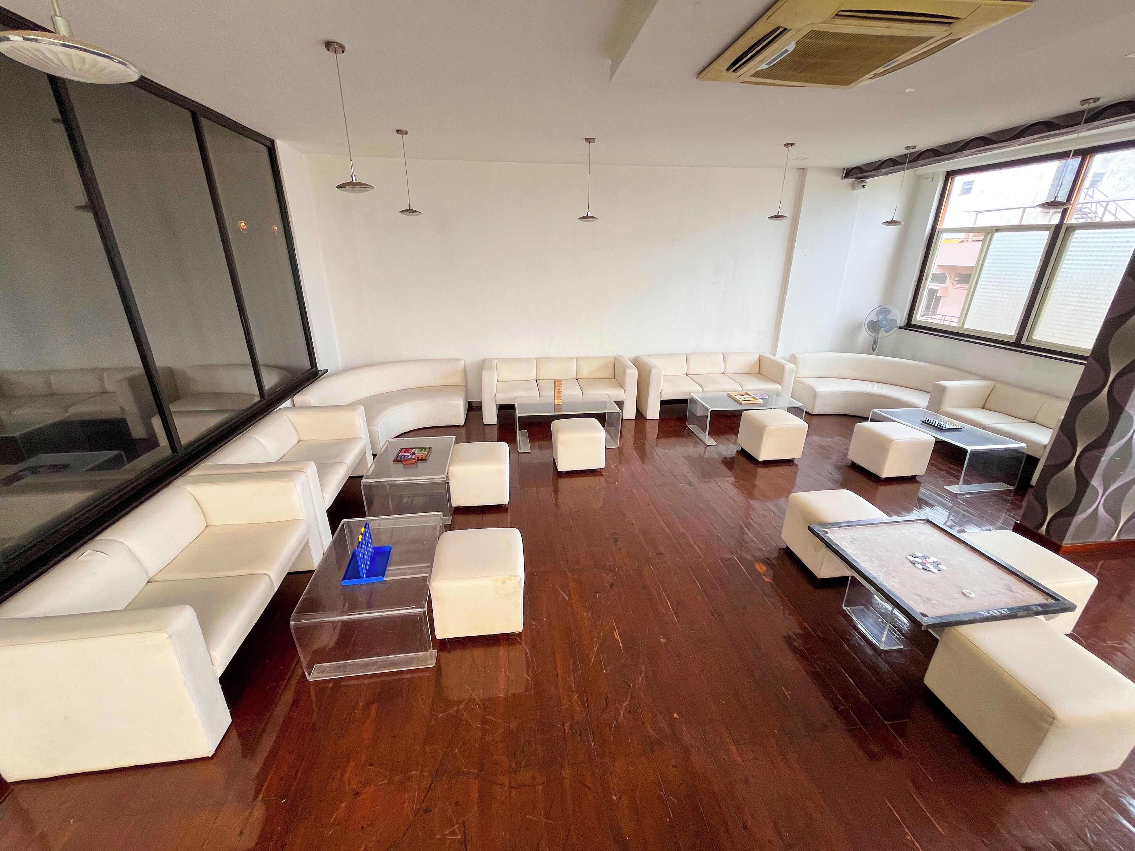 A modern living room with white leather sofas, clear glass coffee tables, and wooden flooring.
