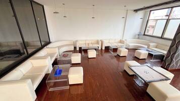 A modern living room with white leather sofas, clear glass coffee tables, and wooden flooring.