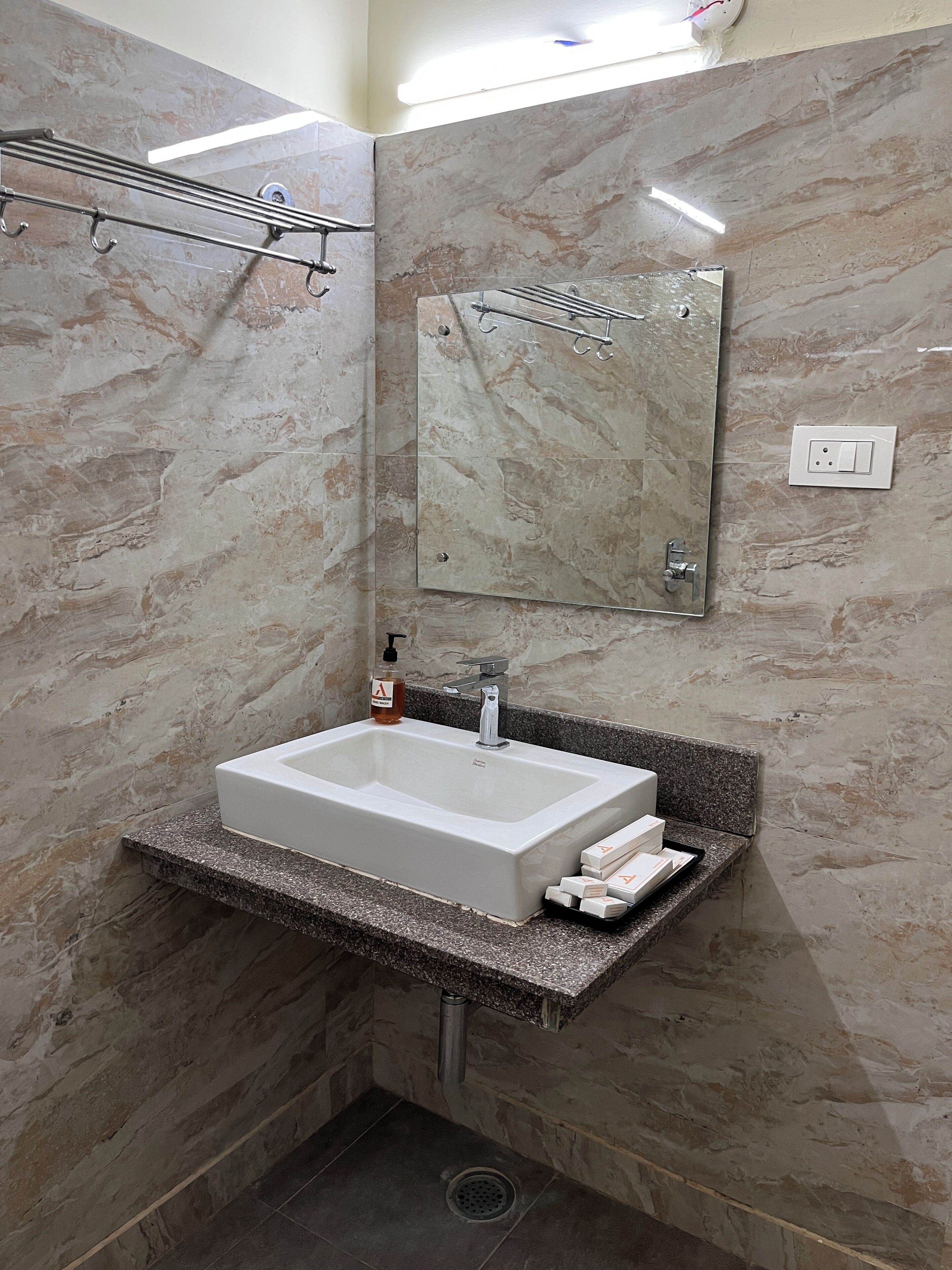 A bathroom with a rectangular sink, a mirror, and a towel rack.