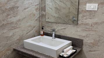 A bathroom with a rectangular sink, a mirror, and a towel rack.