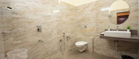 A bathroom with a marble wall, a toilet, a sink, a shower, and a mirror.