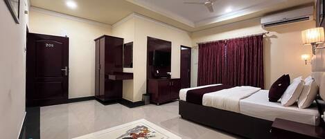 A hotel room with a bed, a desk, a TV, a wardrobe, and a door labeled 205.