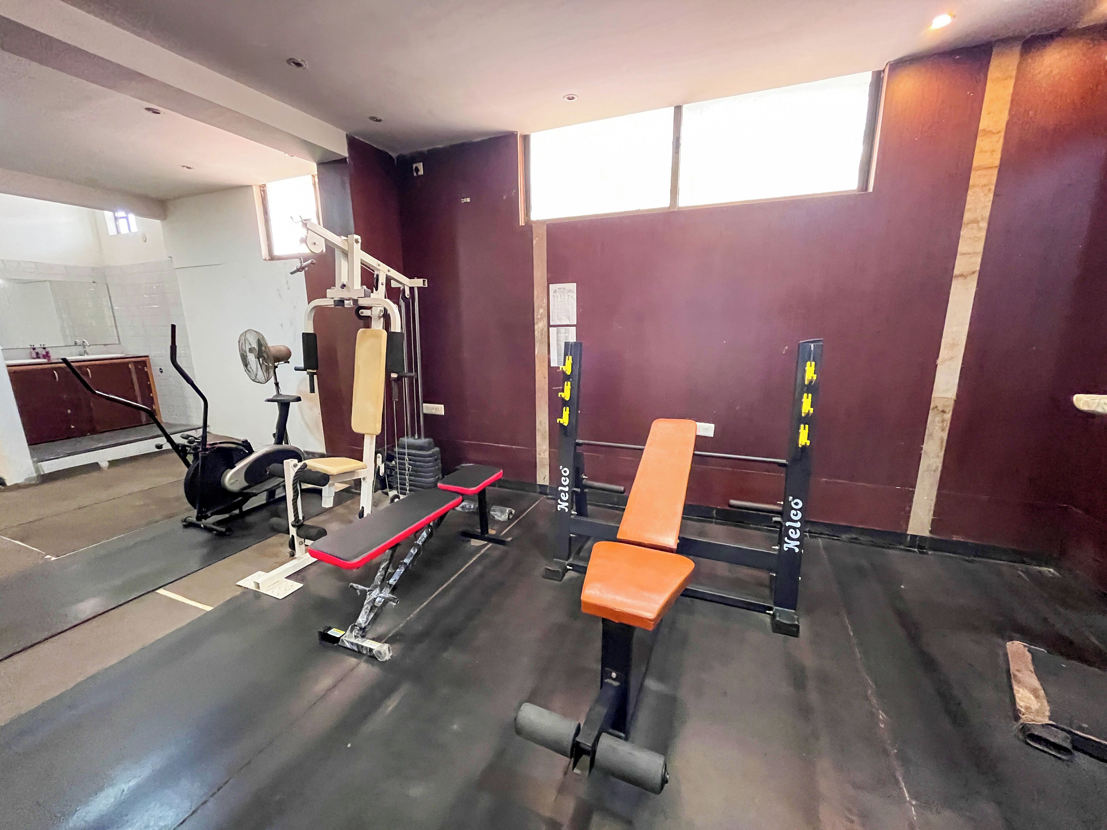 Ein Fitnessstudio mit Gewährleistungsausrüstung, einer Bank und einem Laufband.