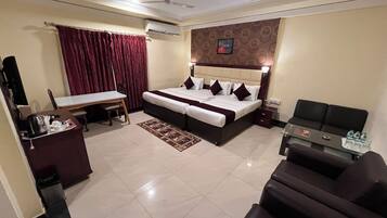 Een hotelkamer met een bed, een bureau, een stoel, een bank en een airconditioning.