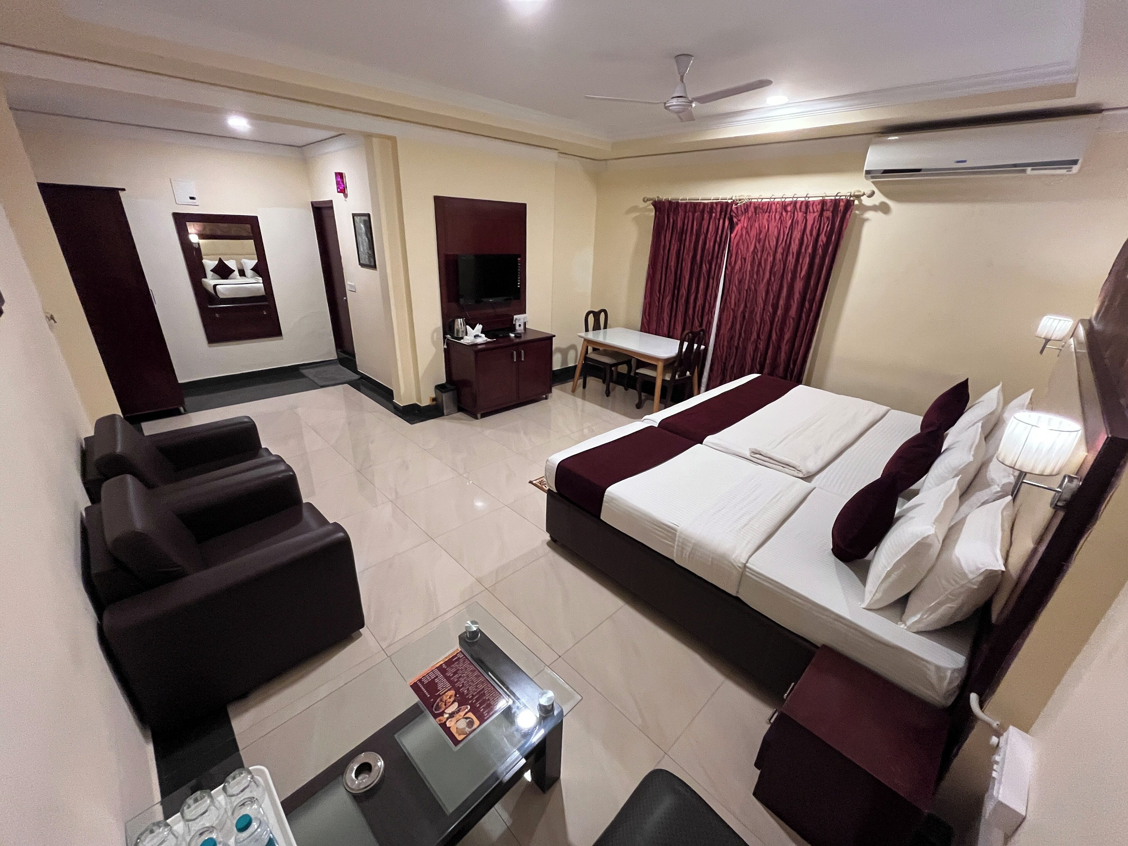 Ein Hotelzimmer mit Bett, Schreibtisch, Stuhl, Sofa und Fernseher.
