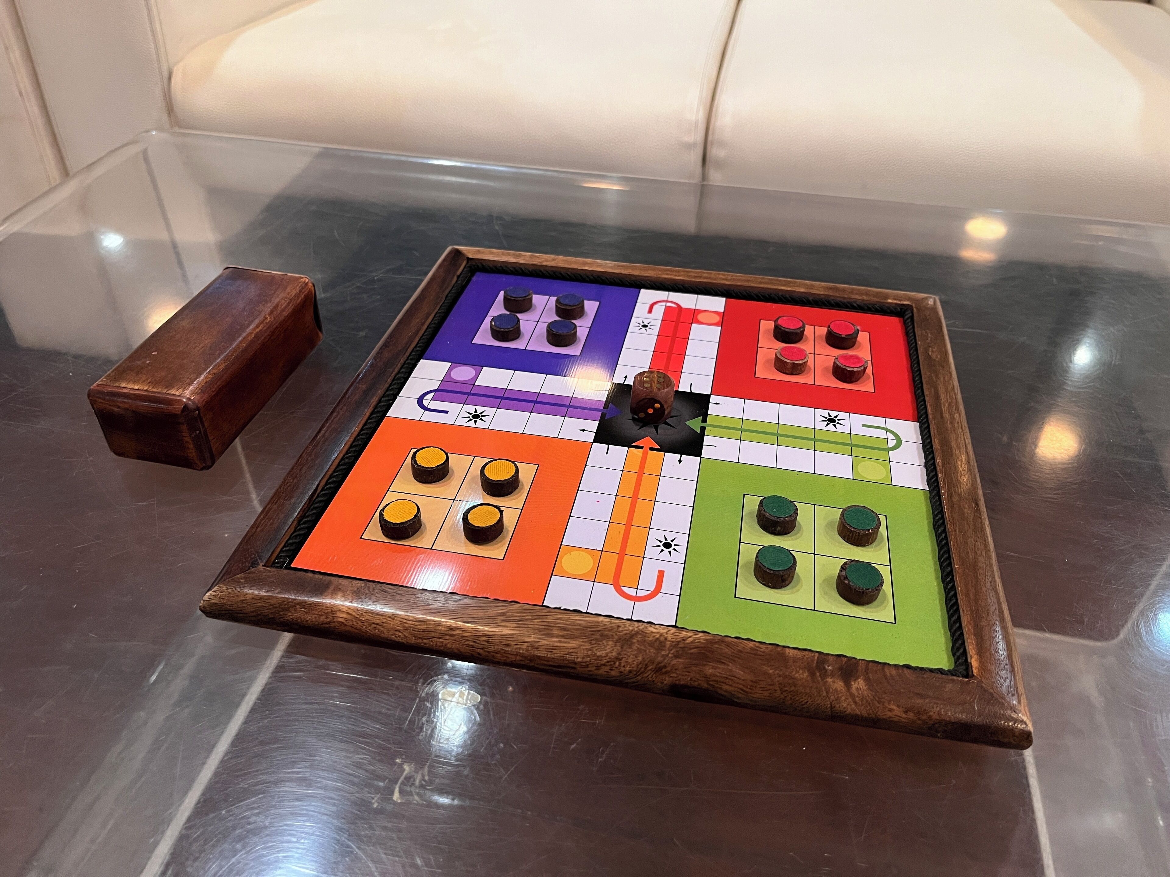 Un juego de mesa a cuadros con marco de madera, sobre una superficie reflectante.