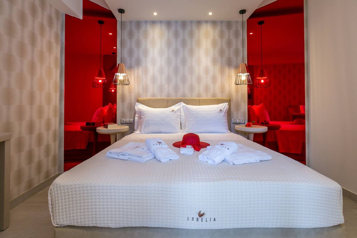 Una habitación de hotel con una cama grande, dos mesitas de noche e iluminación ambiental roja.