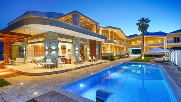 A modern resort with a swimming pool, outdoor seating, and a well-lit patio area. - Lobelia Luxury Suites (Thasos)