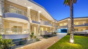 A multi-story hotel with balconies, a central courtyard, and a well-lit exterior. - Lobelia Luxury Suites (Thasos)
