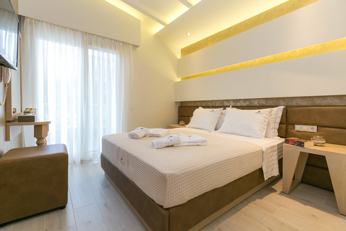Una habitación de hotel moderna con una cama grande, una mesita de noche y una pequeña zona de estar.