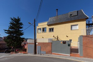 A two-story building with a yellow facade, a brick base, and a grey roof.