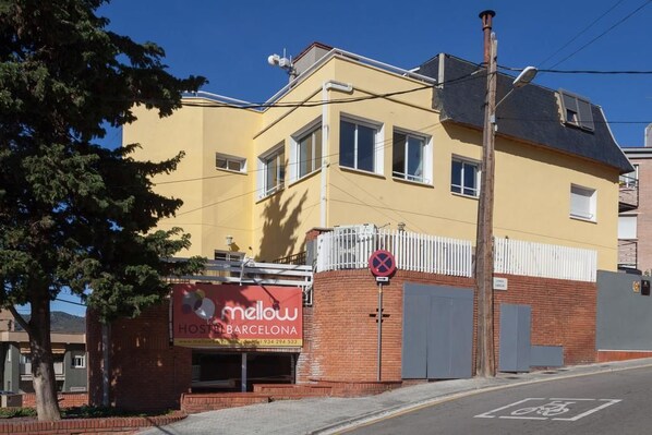 A yellow building with a sign for 'Mellow Hostel Barcelona'.