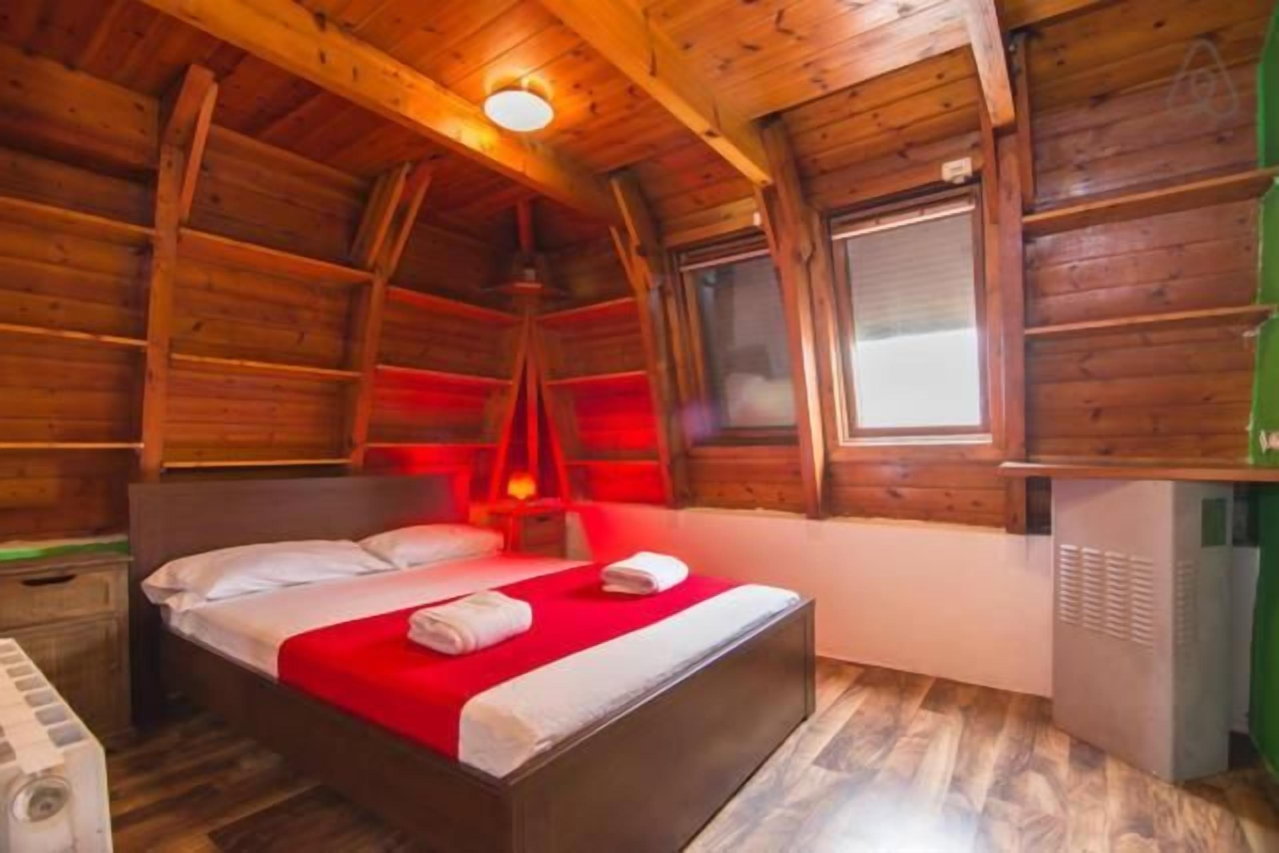Une chambre dans un chalet en bois, avec un lit, un radiateur et une fenêtre.