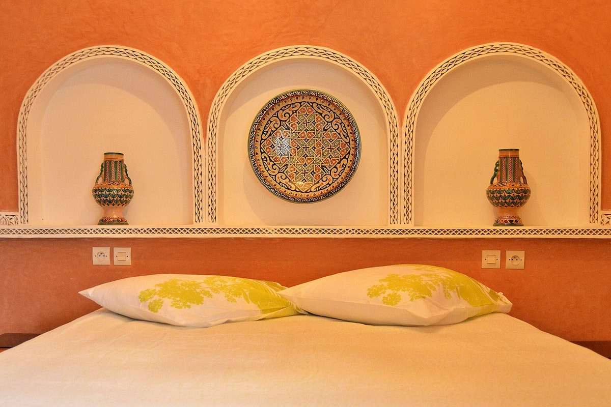 A room with a bed, two decorative vases, and a wall-mounted plate.