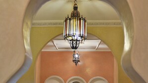 A bedroom with a bed, two chairs, a sofa, a chandelier, and decorative wall arches. - Riad Aicha Marrakech (Marrakech)
