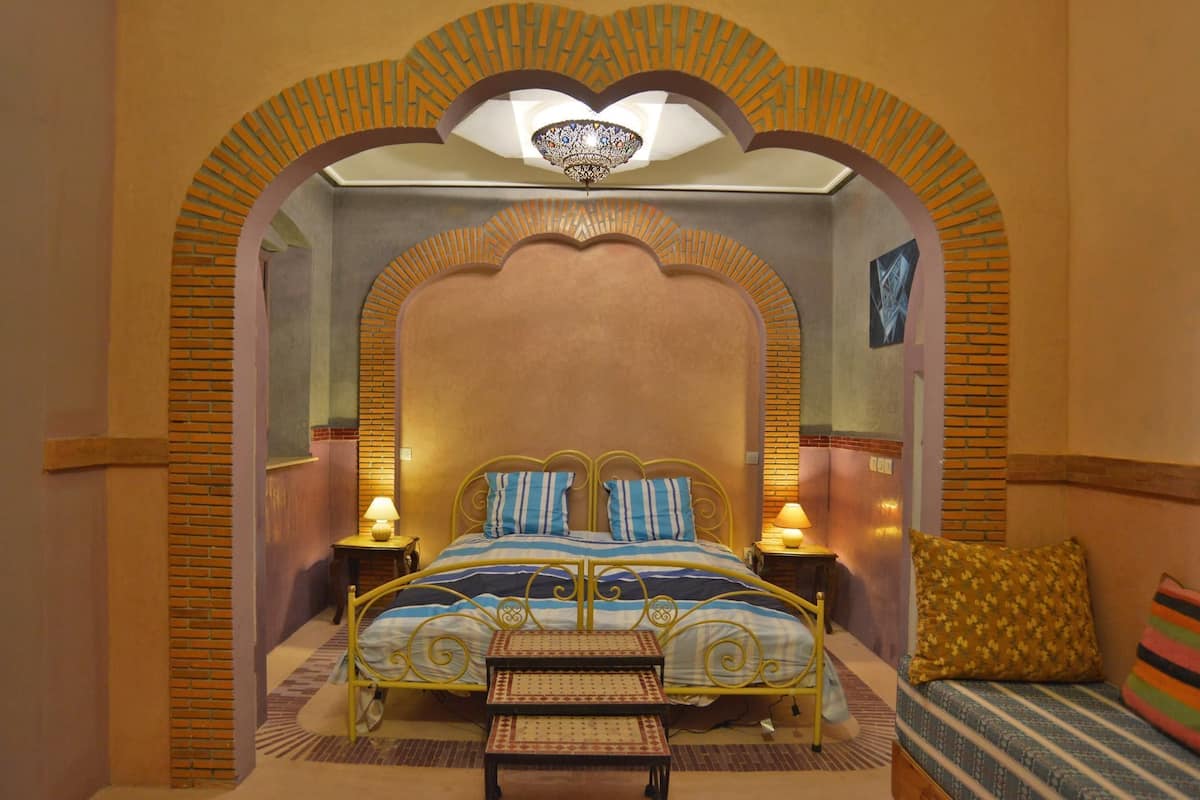 A room with a bed, a bench, and a small table.