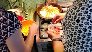 A kitchen with a tiled backsplash, a stove, and a person preparing food. - Riad Aicha Marrakech (Marrakech)