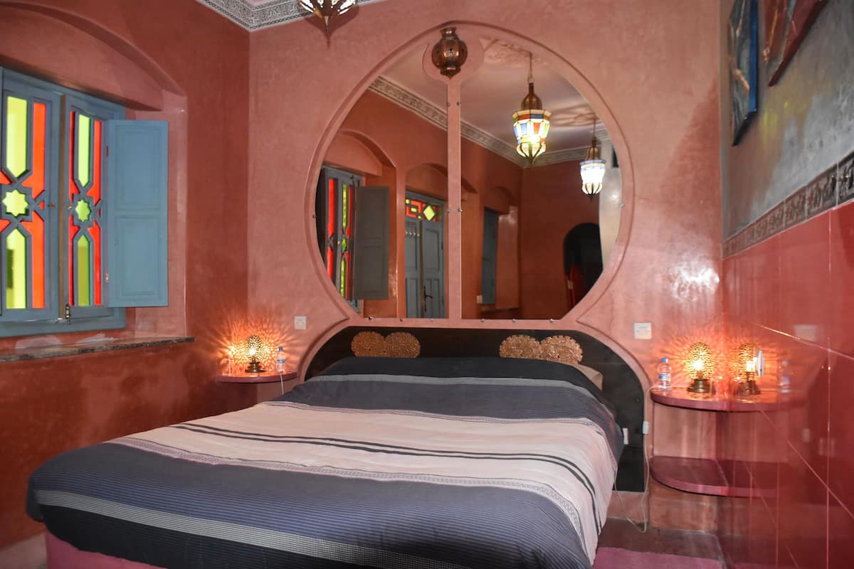A bedroom with a large bed, a mirror, and two bedside tables with lamps.