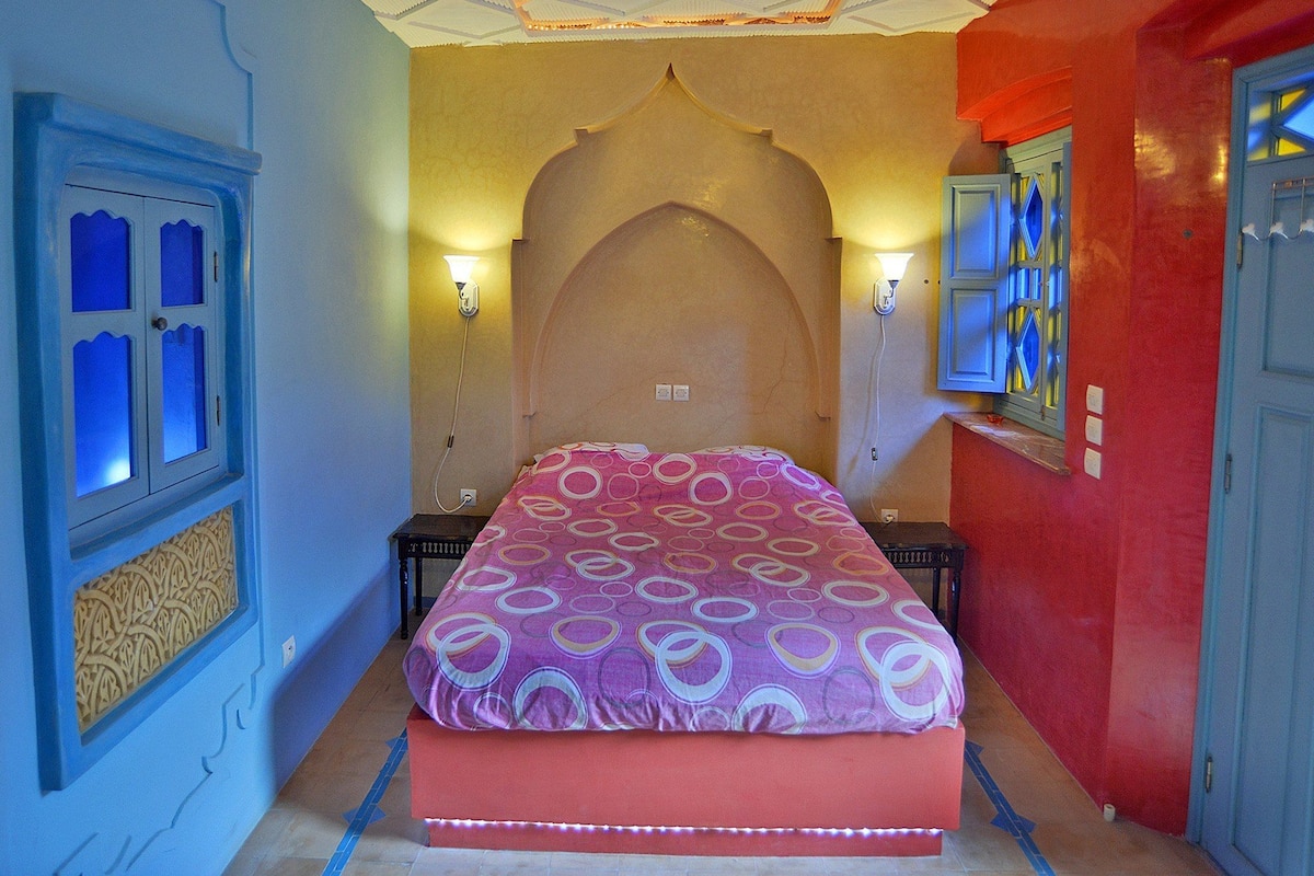 A bedroom with a bed, two nightstands, a decorative wall arch, and two wall-mounted lamps.