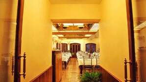 A hotel corridor with tables and chairs arranged for dining, wooden paneling on the walls, and a ceiling with a circular light fixture. - Hotel Shanti Mount Abu (Abu Road)