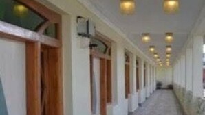 A corridor with wooden-framed windows, a tiled floor, and recessed lighting. - Hotel Shanti Mount Abu (Abu Road)