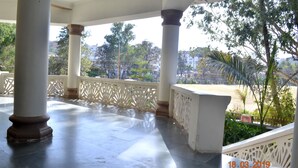 A covered outdoor area with columns and a view of a park. - Hotel Shanti Mount Abu (Abu Road)