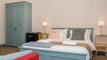 Una habitación de hotel ordenada con cama, armario y mesitas de noche.