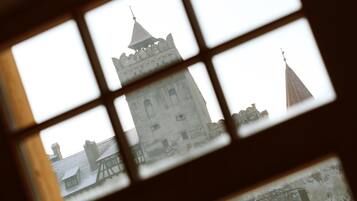 Une vue à travers la fenêtre d’un bâtiment doté d’une tour imposante et d’une structure plus petite surmontée d’un toit en forme de flèche.