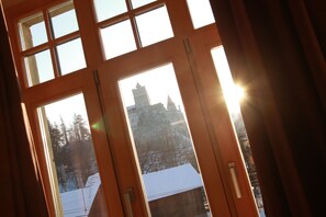 A view through a window with a snowy landscape, including a building with a tower. - Conacul Törzburg (Bran)