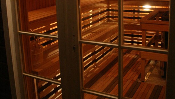 Sauna, jossa on puiset lauteet ja lasiovi.