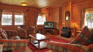 A cozy log cabin interior with a television, fireplace, and comfortable seating. - Ardlui Lodges (Arrochar)