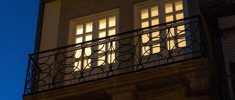 A multi-story building with balconies and windows illuminated at night.