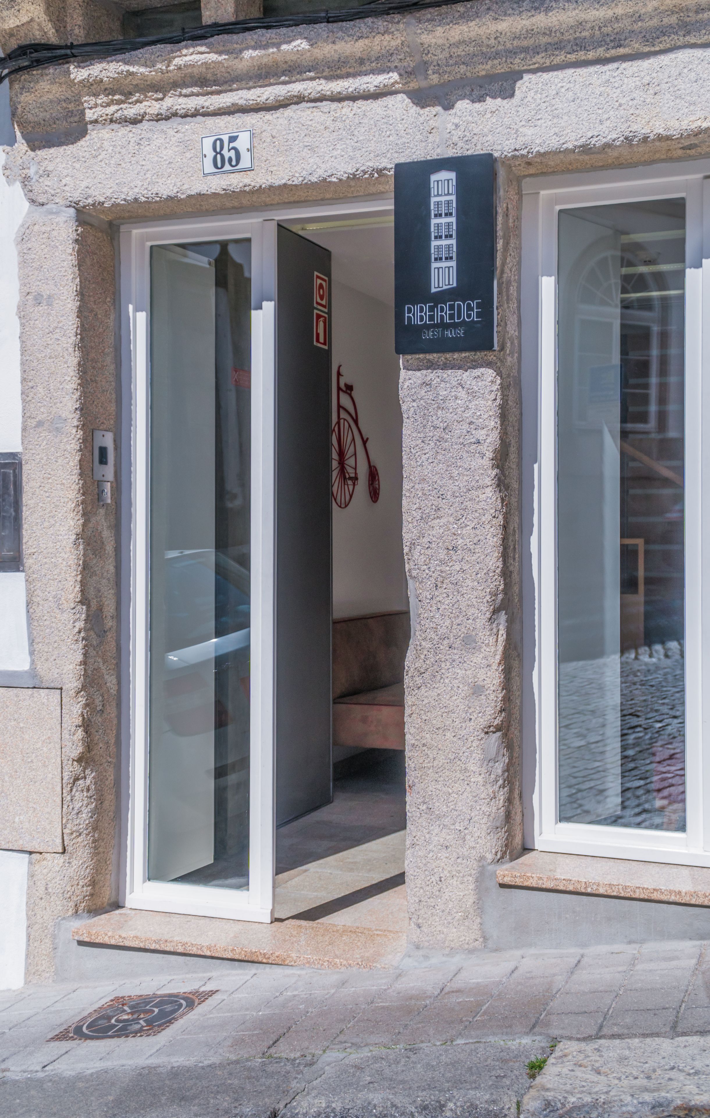 A guest house entrance with a stone facade, numbered 85, and a sign indicating it is a guest house.
