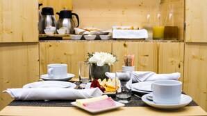 Un esmorzar preparat amb cafè, te, fruita i pastissos damunt d'una taula de fusta.