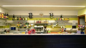 A bar area with shelves of liquor bottles, a coffee machine, and a clock on the wall. - Campodolcino Camping (Campodolcino)