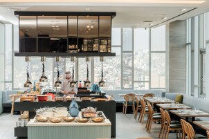 Un comedor moderno con vistas a la ciudad, un chef preparando comida, y una variedad de platos expuestos en la barra.