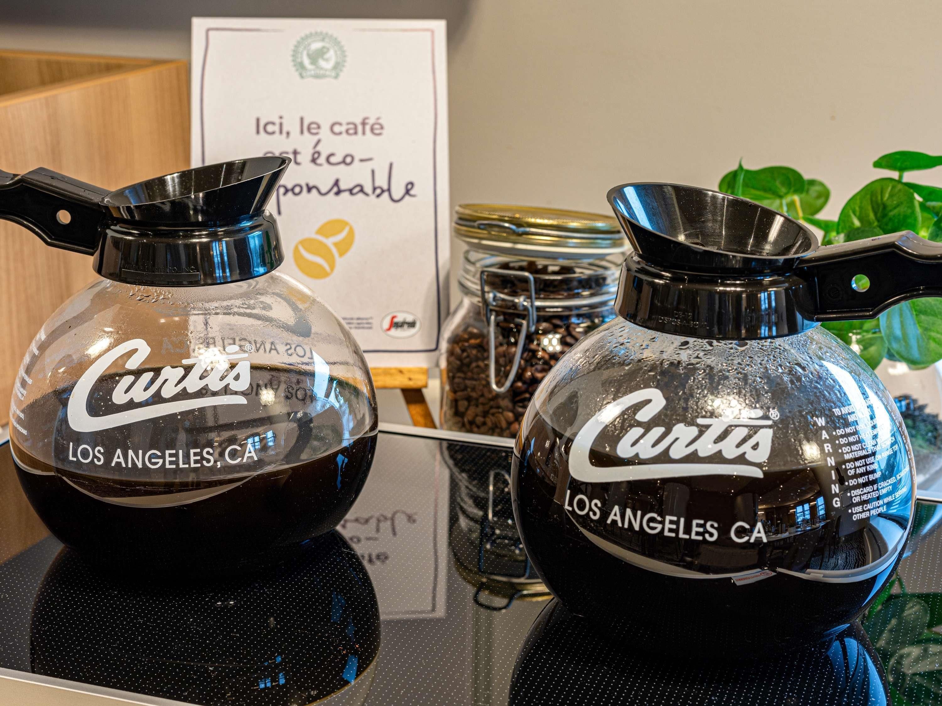 Two coffee machines with 'Curtis Los Angeles CA' labels, a sign in French, and a jar of coffee beans in the background.