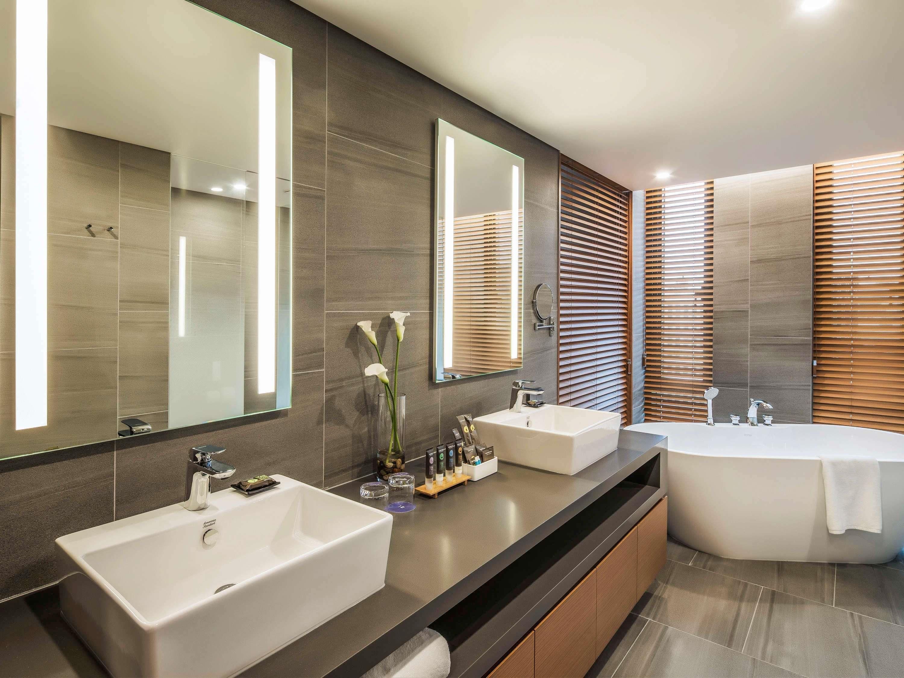 Ein modernes Badezimmer mit zwei Waschbecken, einem großen Spiegel und einer freistehenden Badewanne.