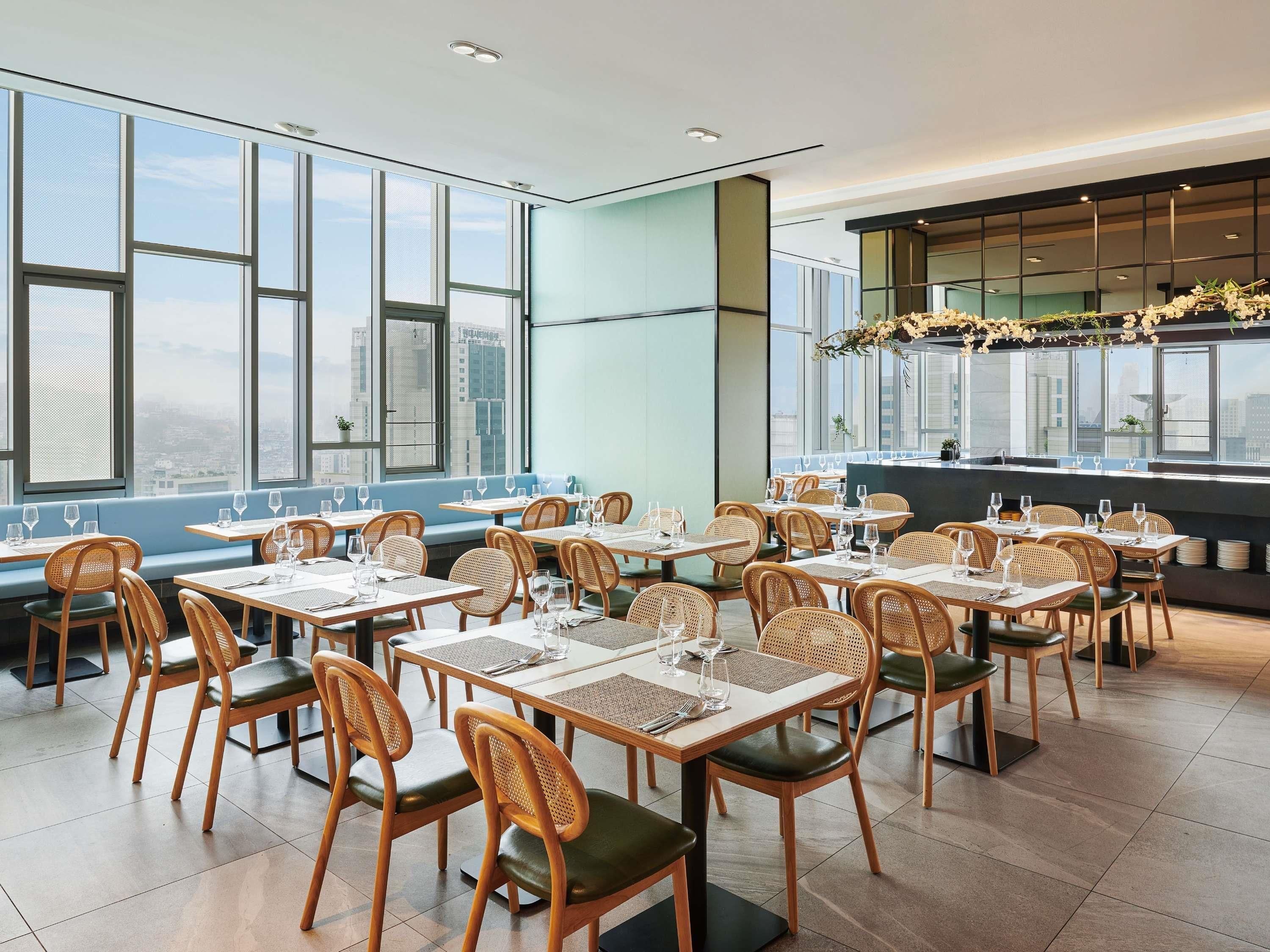 A restaurant with high tables and chairs, large windows, and a city view.
